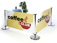Стол кафе окружен барьерными стендами с рекламными плакатами