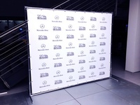 Ant plytelių grindinio stovi reklaminis stendas su firminiais logotipais