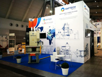 The exhibition stand is covered with a graphic poster, blue carpet, furniture