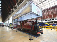 Выставка локомотива с черными конструкциями и плакатами на вокзале