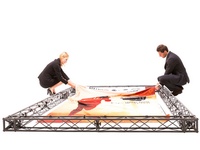 A man and a woman fix a graphic poster on a black construction frame