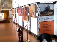 Выставка картин, плакатов и рамок подвешена на черной конструкции стенда.
